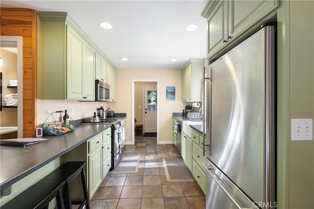 kitchen featuring appliances with stainless steel finishes, dark tile patterned floors, and green cabinetry