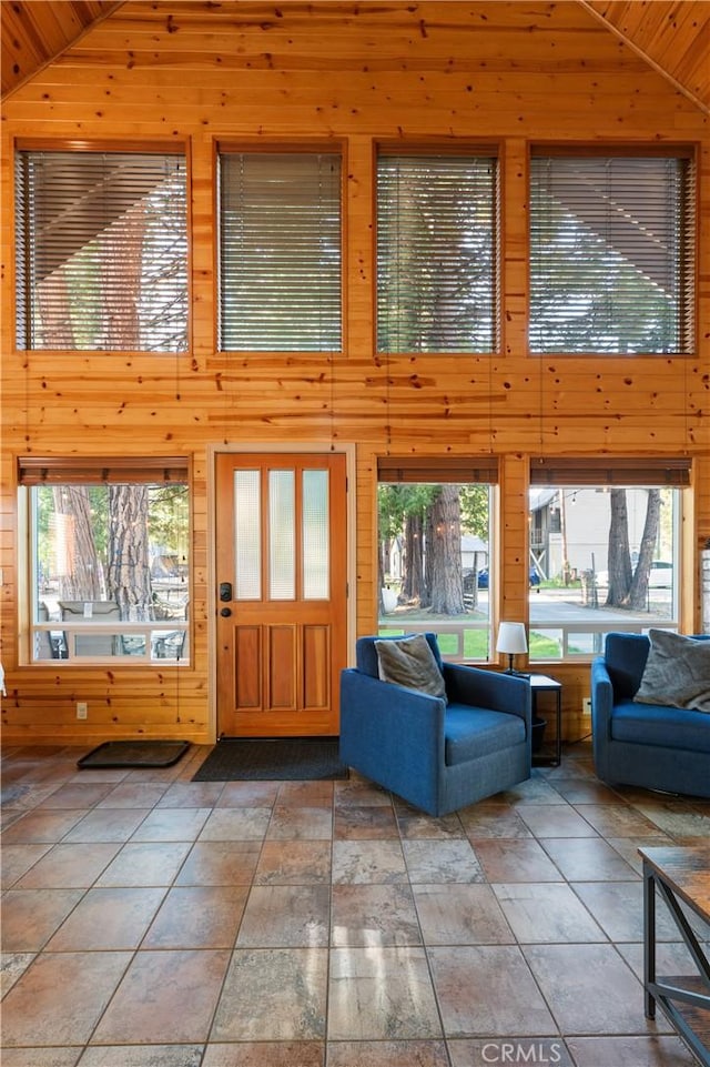 unfurnished living room featuring high vaulted ceiling, wood walls, and wooden ceiling