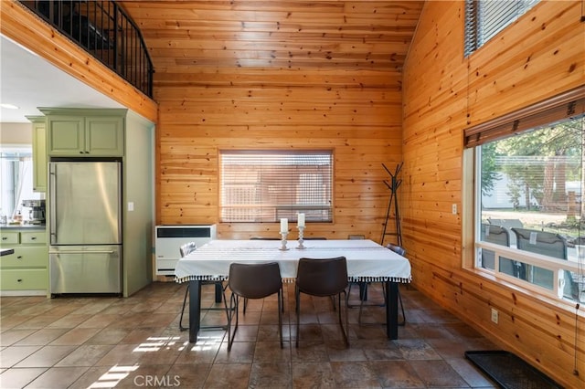 dining room featuring high vaulted ceiling, wooden walls, and heating unit