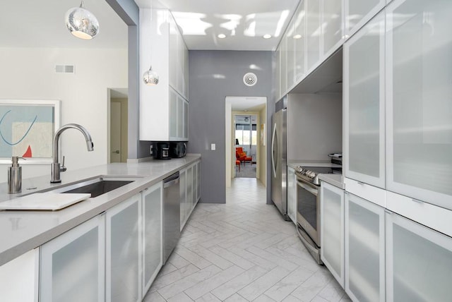 kitchen featuring sink, pendant lighting, white cabinets, and stainless steel appliances