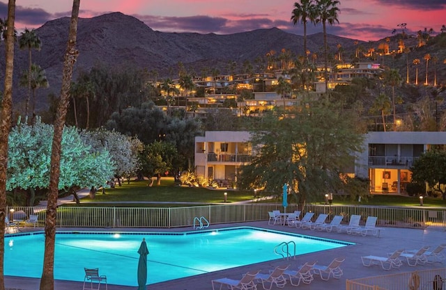 pool at dusk featuring a mountain view and a patio