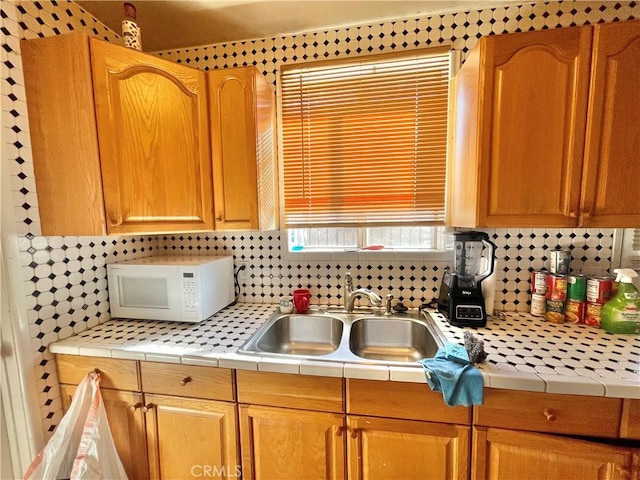 kitchen featuring tile counters, backsplash, and sink