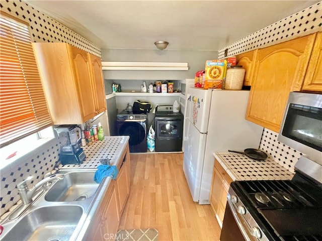 kitchen featuring light hardwood / wood-style floors, washer and dryer, stainless steel appliances, backsplash, and sink