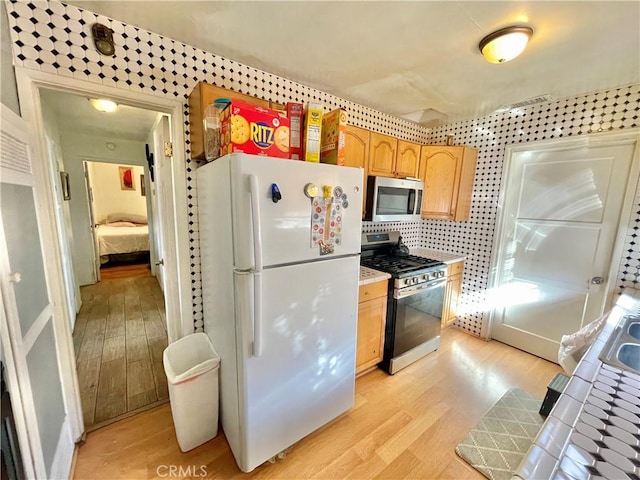 kitchen featuring stainless steel appliances, decorative backsplash, light hardwood / wood-style floors, and tile counters