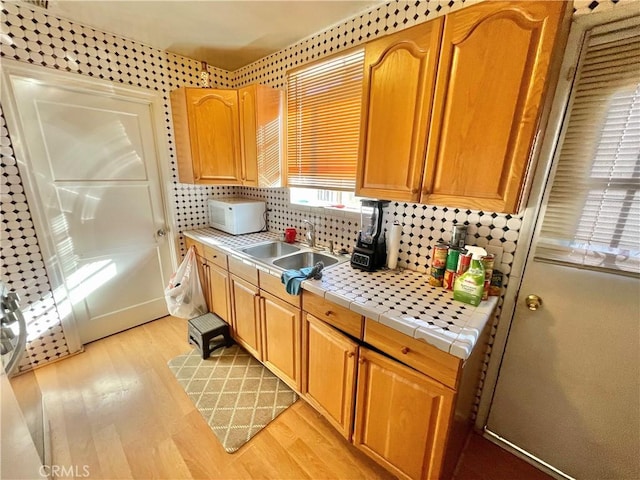 kitchen with backsplash, sink, tile countertops, and light hardwood / wood-style floors