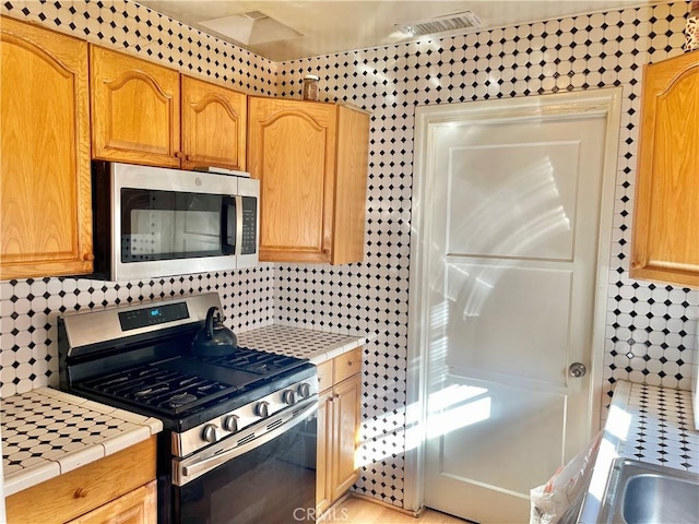 kitchen featuring tile counters, decorative backsplash, and stainless steel appliances