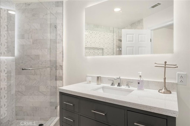 bathroom with tiled shower and vanity