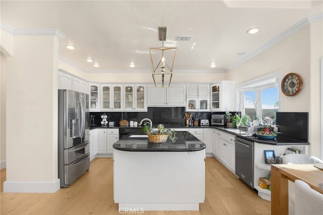 kitchen with a center island, white cabinetry, stainless steel appliances, decorative backsplash, and sink