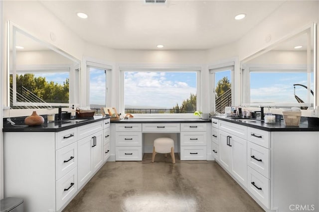 interior space with sink, white cabinetry, and concrete flooring