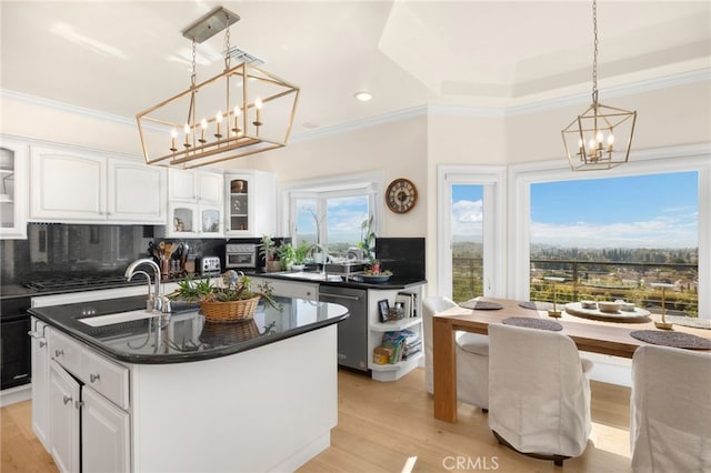 kitchen with decorative light fixtures, white cabinetry, appliances with stainless steel finishes, and a kitchen island with sink