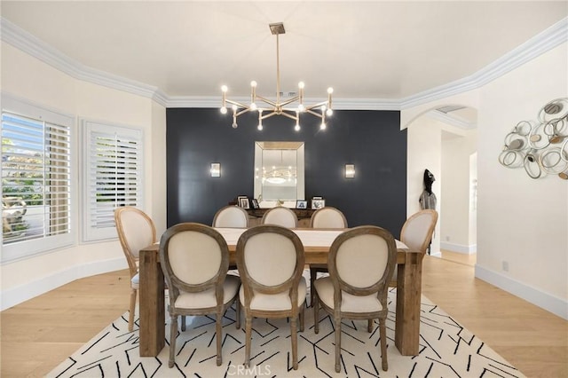 dining area with light hardwood / wood-style flooring, crown molding, and an inviting chandelier