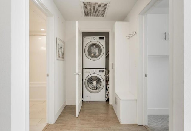 washroom with stacked washer and clothes dryer and light hardwood / wood-style floors