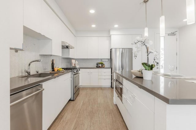 kitchen featuring extractor fan, appliances with stainless steel finishes, decorative light fixtures, tasteful backsplash, and white cabinetry