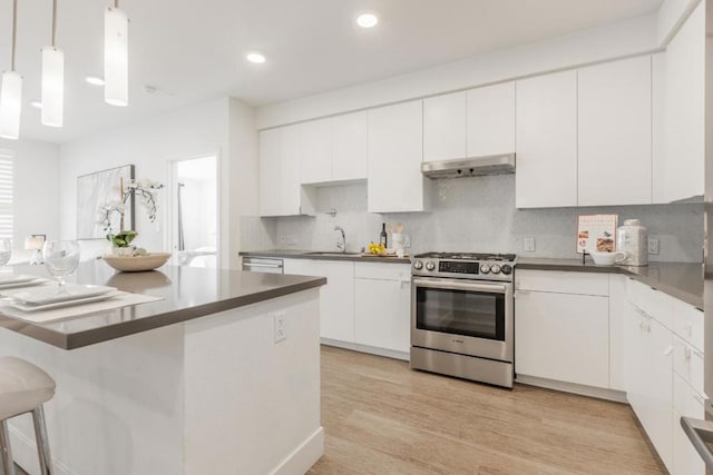 kitchen with stainless steel range with gas cooktop, pendant lighting, white cabinets, decorative backsplash, and light hardwood / wood-style floors