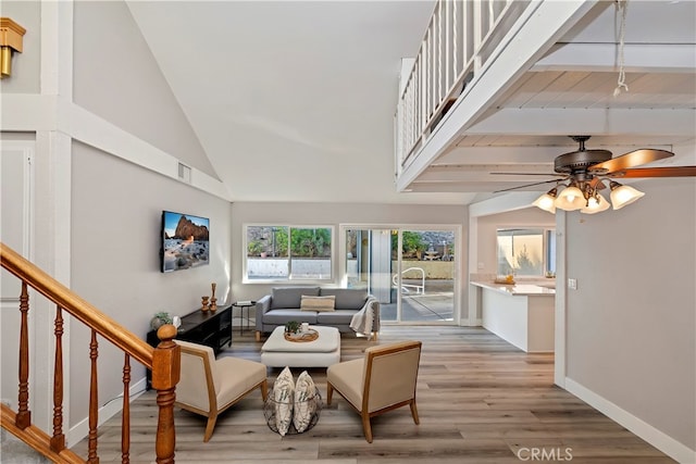 living room featuring ceiling fan, a high ceiling, and light hardwood / wood-style flooring