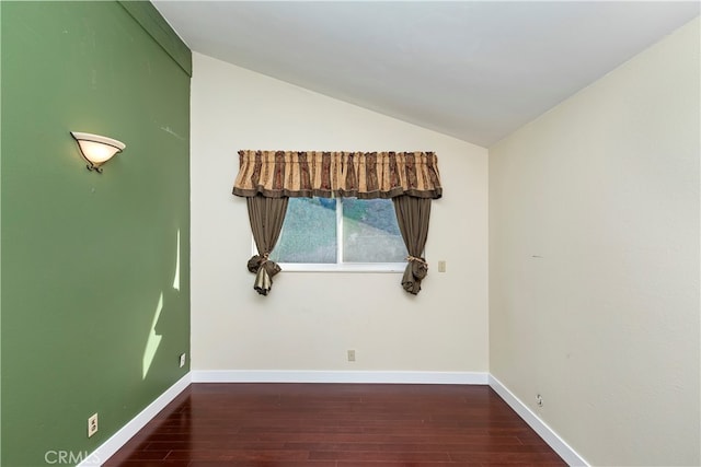 empty room with dark wood-type flooring and lofted ceiling