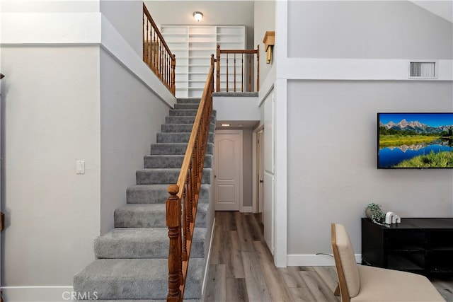 stairs with a high ceiling and hardwood / wood-style floors