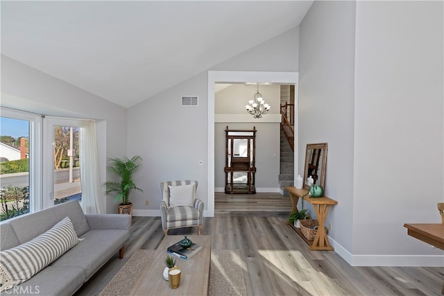 living room with light hardwood / wood-style floors, high vaulted ceiling, and a chandelier