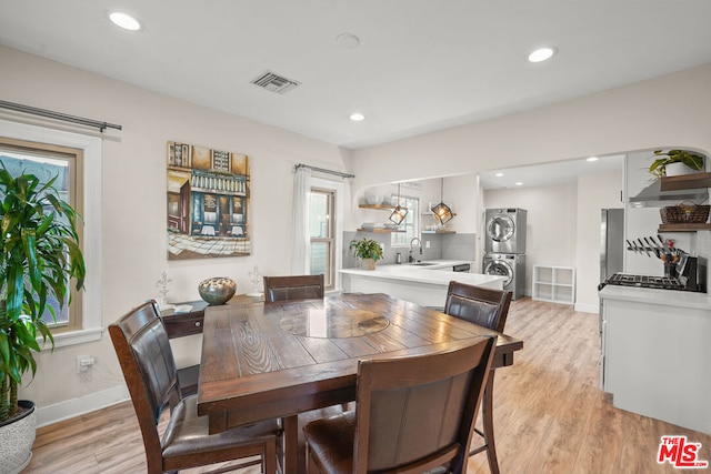 dining space with stacked washer and dryer, sink, and light hardwood / wood-style flooring