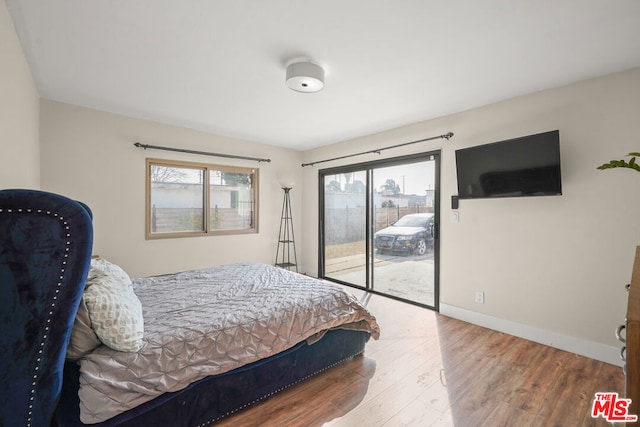 bedroom featuring multiple windows, hardwood / wood-style flooring, and access to outside