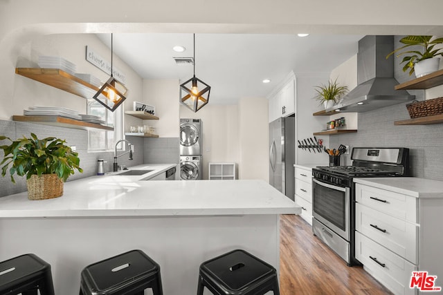 kitchen with sink, decorative light fixtures, kitchen peninsula, stainless steel appliances, and exhaust hood