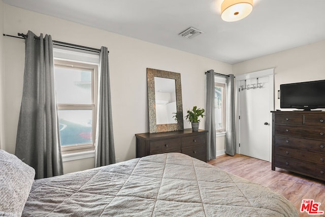 bedroom with multiple windows and light hardwood / wood-style flooring