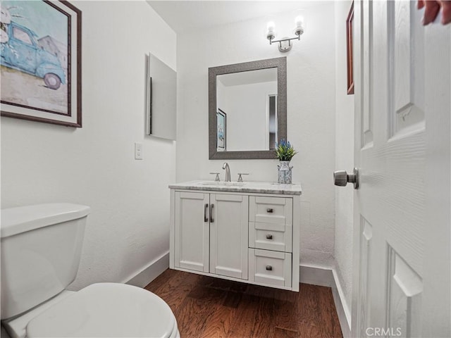 bathroom with toilet, vanity, and hardwood / wood-style flooring