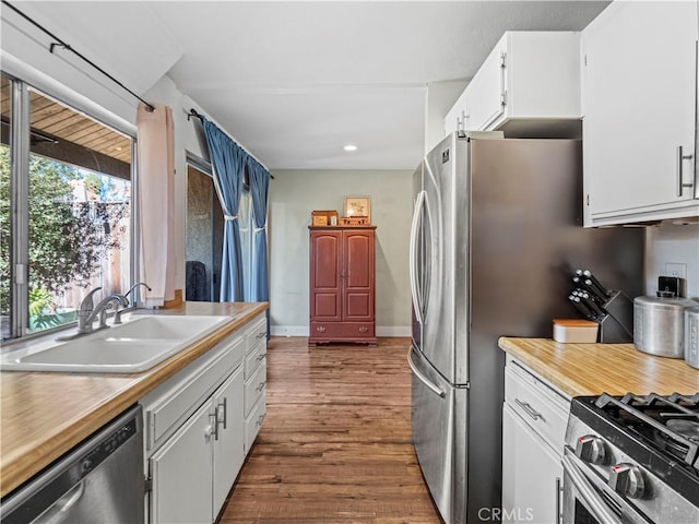 kitchen with white cabinets, appliances with stainless steel finishes, sink, and dark hardwood / wood-style floors