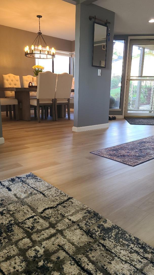 interior space with a healthy amount of sunlight, an inviting chandelier, and hardwood / wood-style flooring