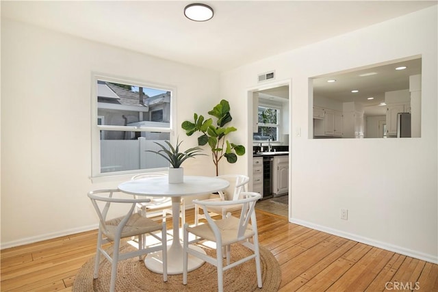 dining space featuring plenty of natural light, sink, and light hardwood / wood-style flooring