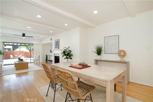 dining space with ceiling fan, beamed ceiling, and light hardwood / wood-style floors