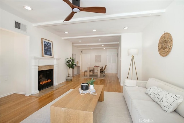 living room featuring ceiling fan, beam ceiling, and light hardwood / wood-style flooring