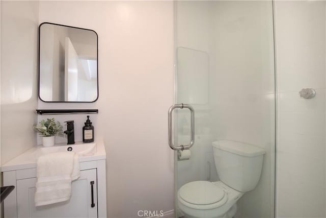 bathroom with a shower with door, toilet, and vanity