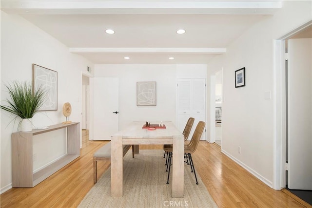 dining space with light wood-type flooring and beamed ceiling