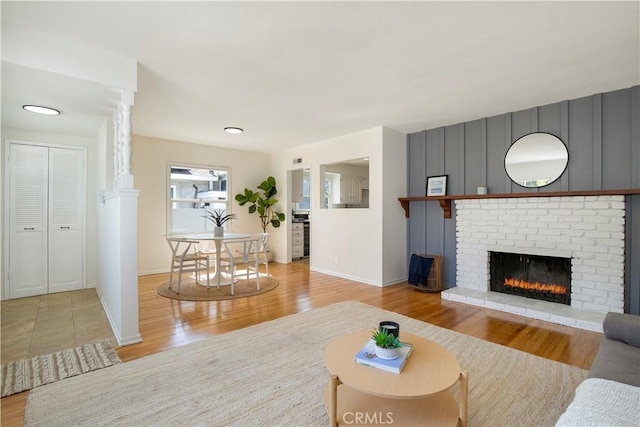 living room featuring a brick fireplace and light hardwood / wood-style floors