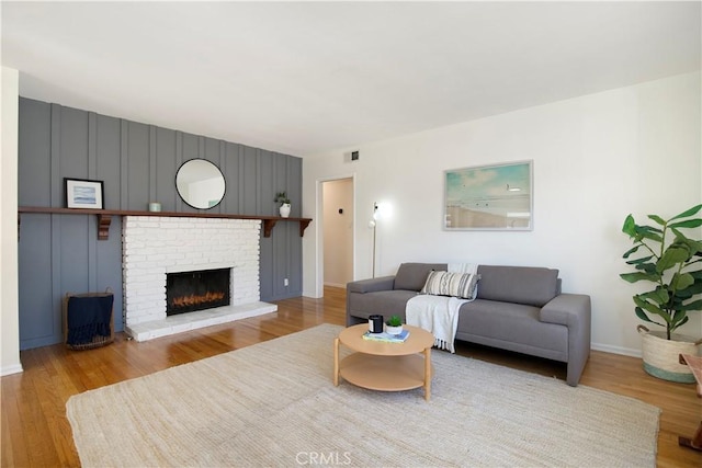 living room featuring a brick fireplace and light wood-type flooring