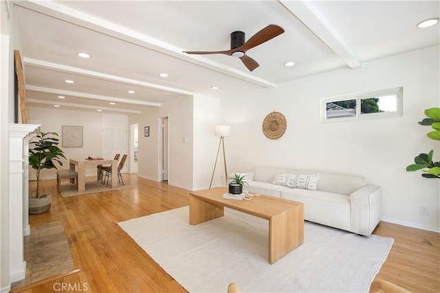 living room featuring ceiling fan, light hardwood / wood-style flooring, and beamed ceiling