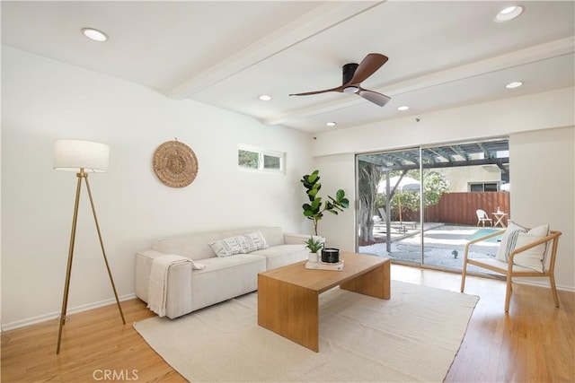 living room with light hardwood / wood-style floors, ceiling fan, and beamed ceiling