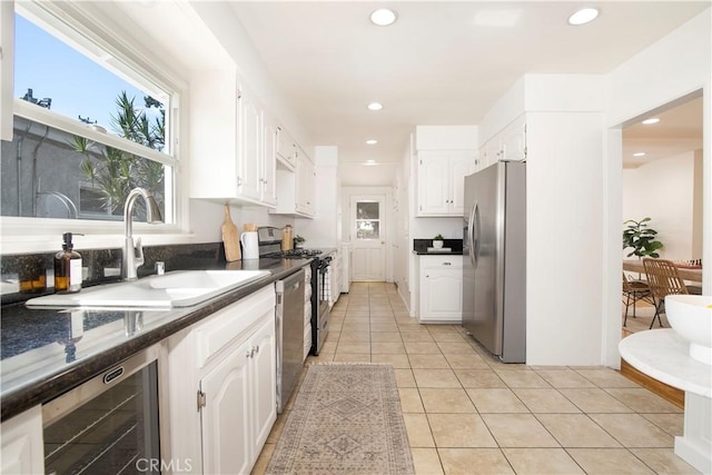 kitchen featuring beverage cooler, appliances with stainless steel finishes, white cabinetry, sink, and light tile patterned floors