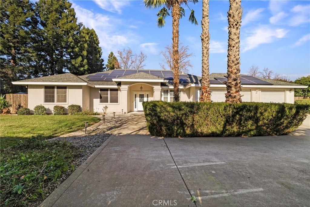 single story home featuring a garage, a front lawn, and solar panels