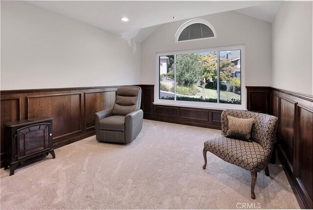 living area with a wood stove, light carpet, and vaulted ceiling