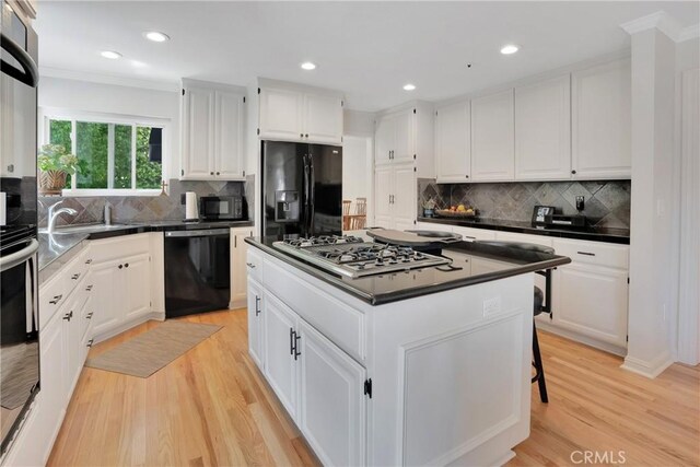 kitchen with black appliances, white cabinetry, and a center island