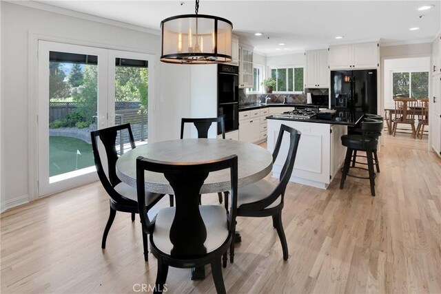 dining area featuring a healthy amount of sunlight, a notable chandelier, and light wood-type flooring