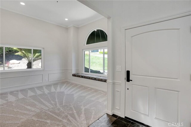 carpeted foyer entrance with plenty of natural light and ornamental molding