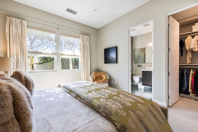 bedroom featuring a walk in closet, ensuite bathroom, carpet, and a closet