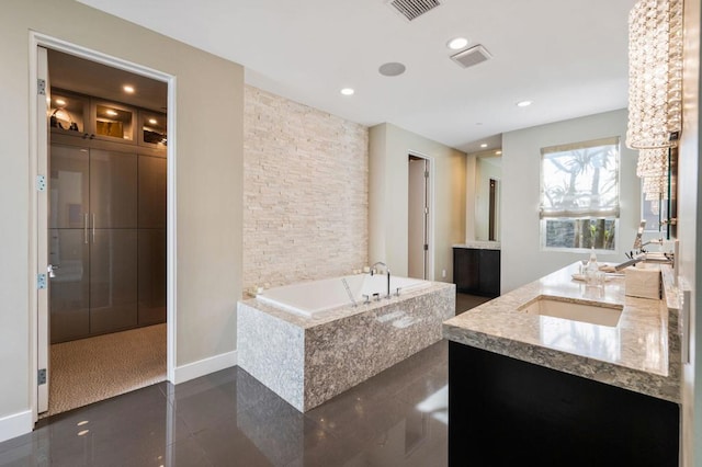 bathroom with vanity, tiled bath, and tile patterned flooring