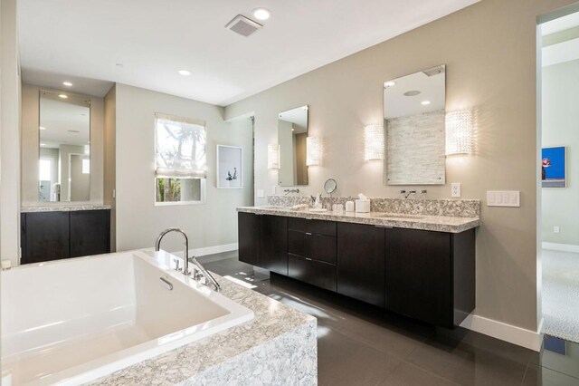 bathroom featuring tiled tub, vanity, and tile patterned flooring