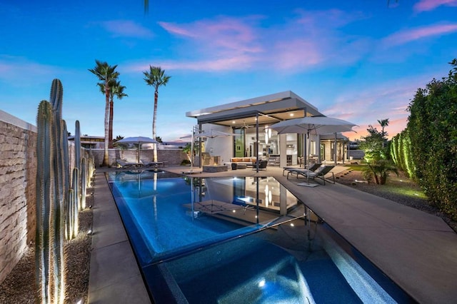 pool at dusk with a patio area