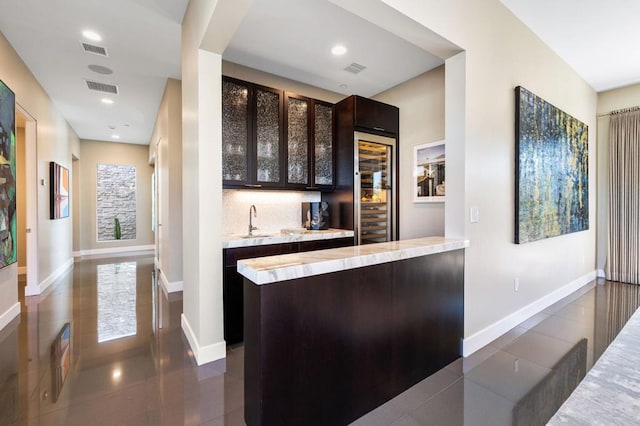 bar with dark brown cabinets, dark tile patterned flooring, sink, and decorative backsplash