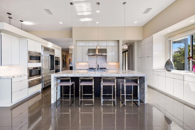 kitchen with white cabinetry, a large island, tasteful backsplash, and pendant lighting